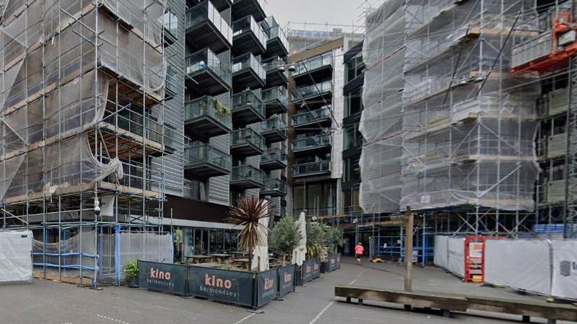 Streetview image of the Kino cinema building below an apartment block surrounded with scaffolding