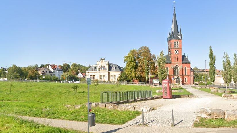 Grassy area in Bad Hersfeld with red brick church and red phone box