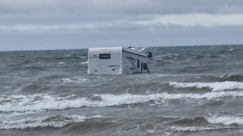 Llun o camperfan yng nghanol y môr gyda thonnau o'i gwmpas.