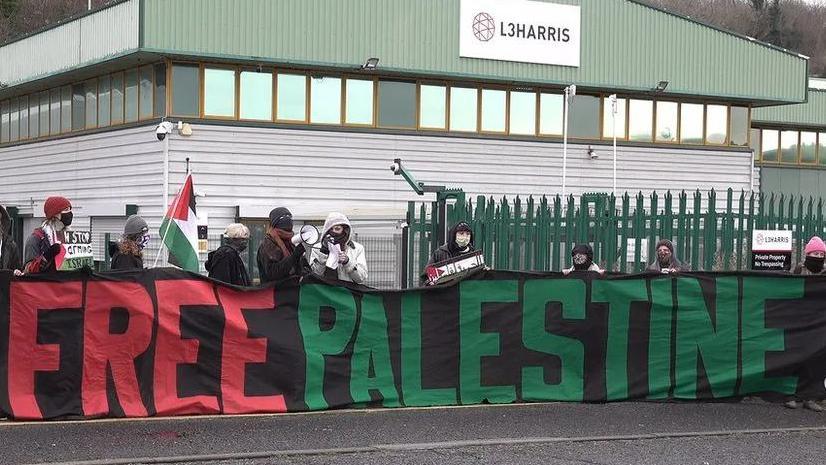 Protesters outside the L3 Harris factory in Brighton holding a sign reading Free Palestine