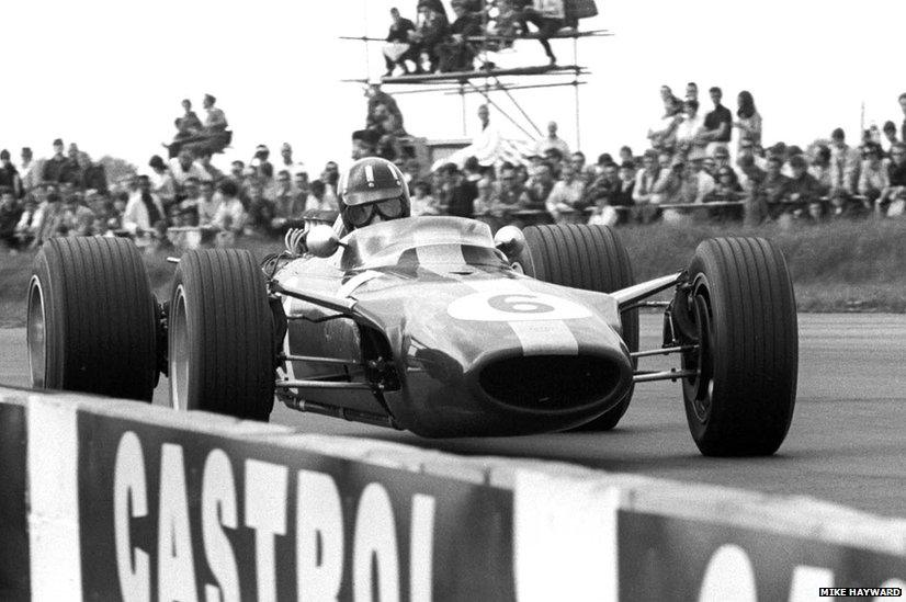 Graham Hill looks straight at the camera at Copse Corner, Silverstone