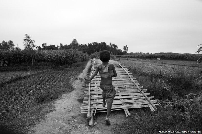 A little boy runs across a makeshift bamboo bridge.