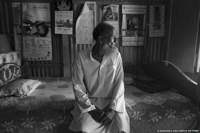 Mohammad Mansoor Ali Mia sitting on a bed in his home