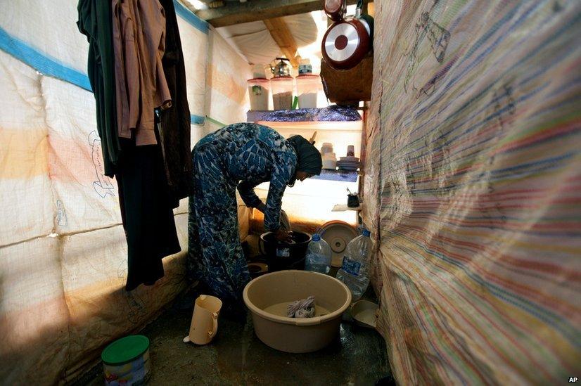 Syrian refugee, Khadija Mohammed washes clothes inside her tent, at a temporary refugee camp in the eastern Lebanese town of Faour near the border with Syria, Lebanon.