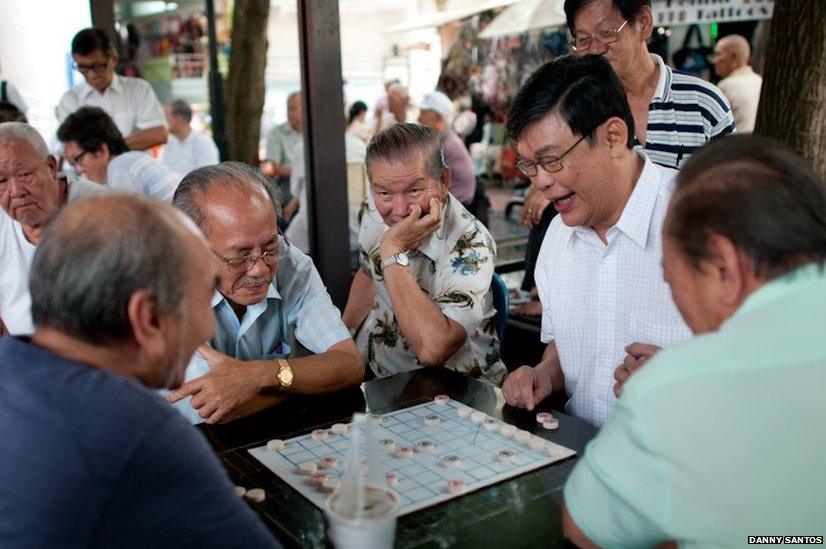 A group playing Xiangqi, sometimes called Chinese chess, in Chinatown where you will find groups playing every day.