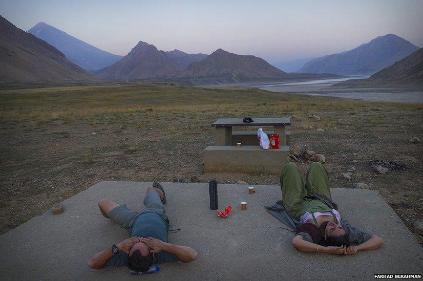 Two people relax near a river