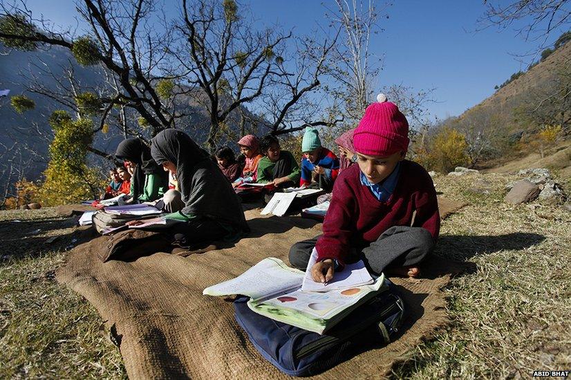 Kashmiri Muslim children of a primary school study in the open near the Line of Control, in Silikote village, some 125 km north of Srinagar