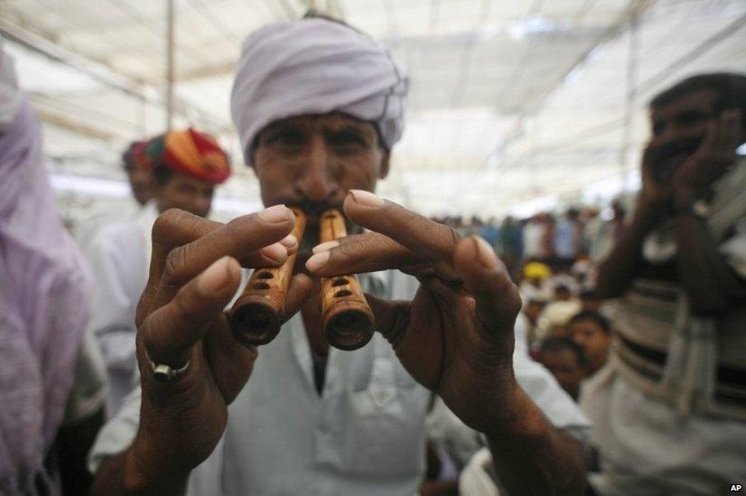 Indian village man plays a traditional wind instrument at an election campaign rally addressed by Congress party vice president Rahul Gandhi in Rajasthan.