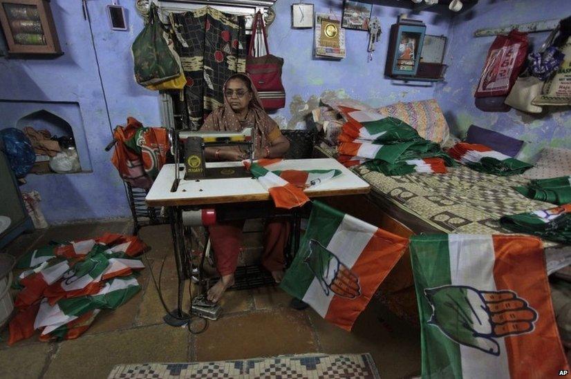 Indian woman stitches Congress party flags ahead of parliamentary elections in Ahmedabad.