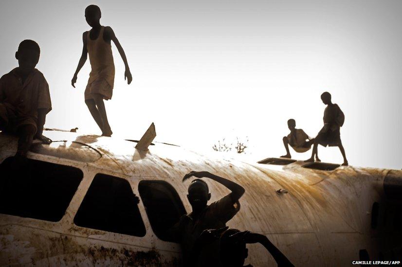 Young refugees play on an aircraft that crashed in November 2012 on the Yida airstrip, South Sudan