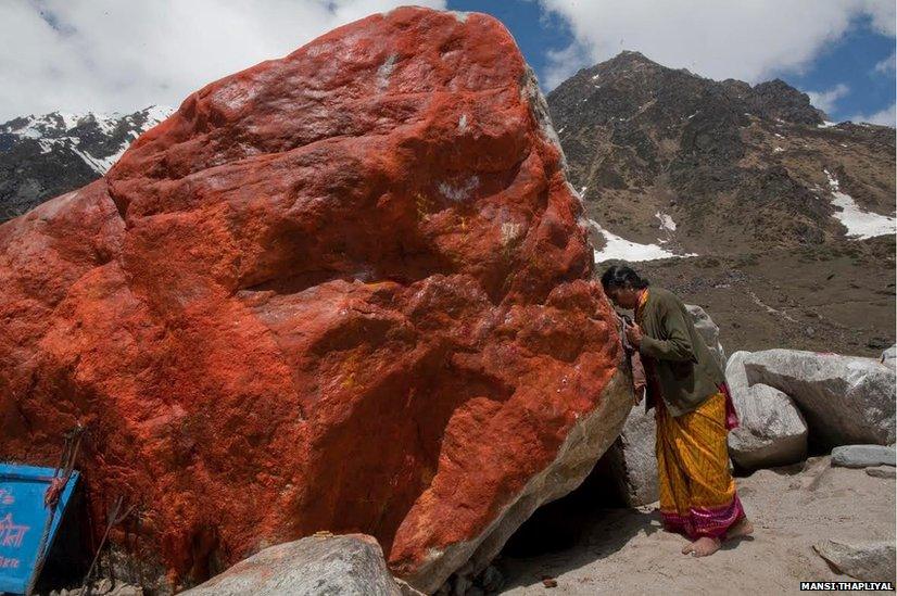 A pilgrim offers prayers to a large stone with its side painted saffron. The rock helped divert flood waters away from the temple in Kedarnath last year, that’s why many today believe it to be sacred.