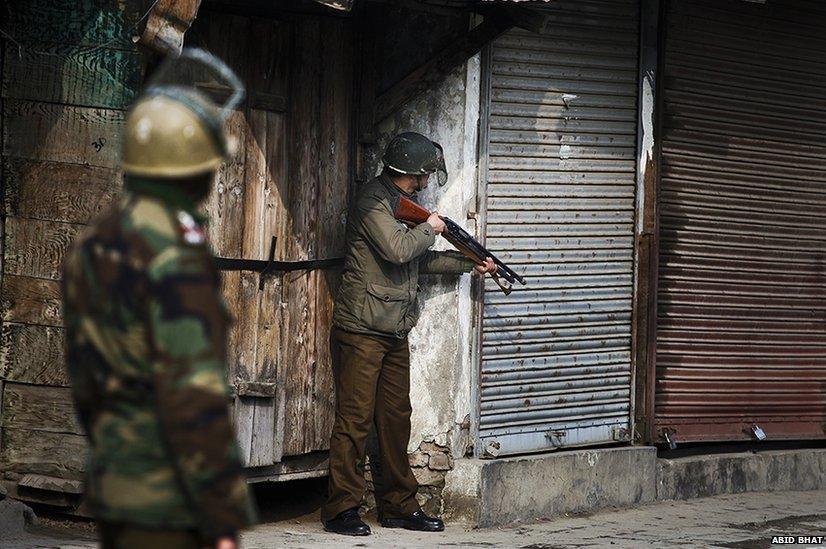 A policeman aims his pellet gun at the group of Kashmiri protesters during a strike in Srinagar, the summer capital of Indian Kashmir, January 31 2014.