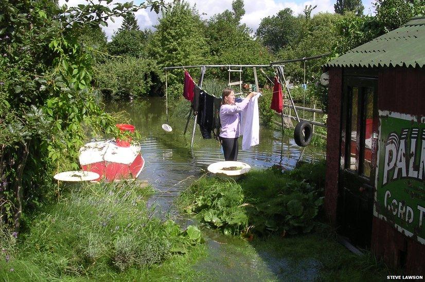 Woman hanging washing in flooded garden