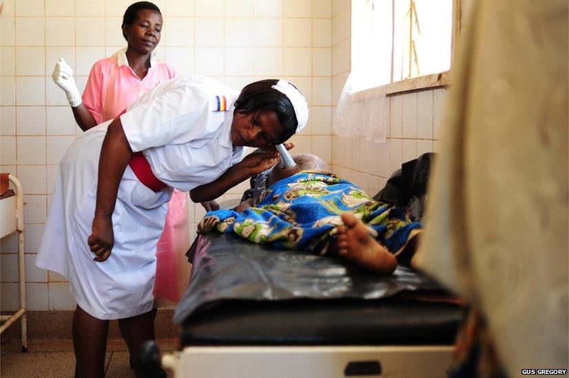 A midwife listens to the heartbeat of an unborn baby