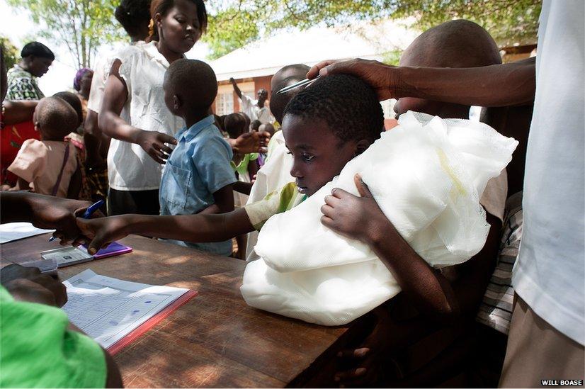 A child is handed a mosquito net