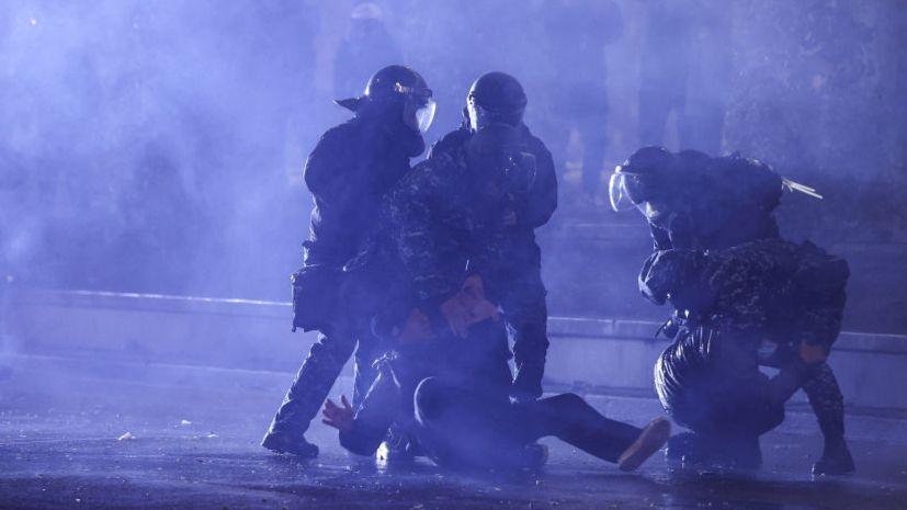 Police bundle a protester in Georgia to the ground on a darkened street in the capital