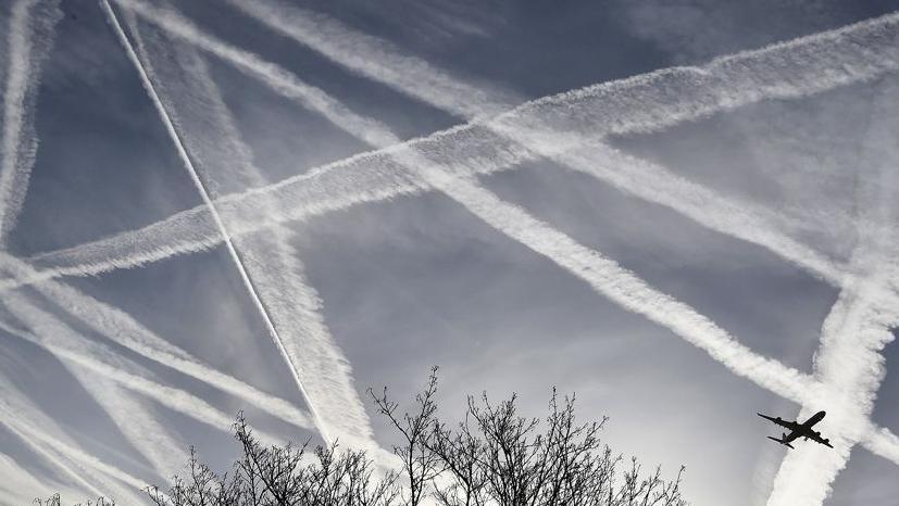 Aeroplane flies through a sky full of condensation trails