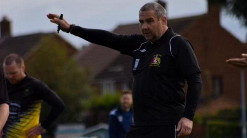 Michael Giblin refereeing on a football pitch, wearing black