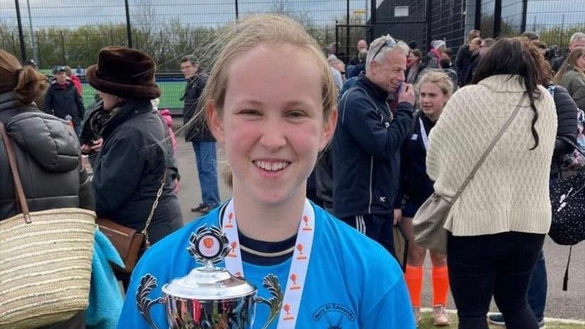 Georgia Scarff in a blue kit, holding a silver trophy 