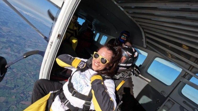 Tamsin wearing yellow rimmed sunglasses and about to jump out of a plane to complete a skydive.