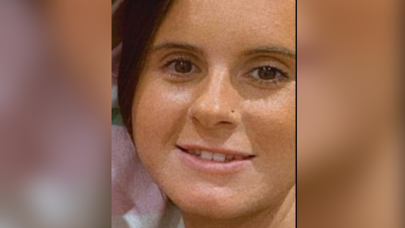 A young woman's face is seen close up. She has dark hair and eyes and is smiling.