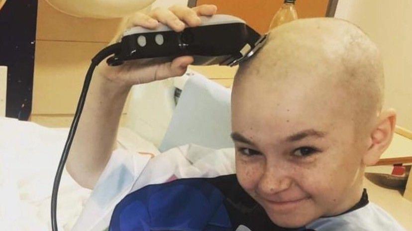 Young boy in bed shaving his head 