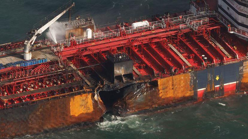 Close-up of the side of Stena Immaculate showing a large hole in its hull and signs of fire damage to the deck.
