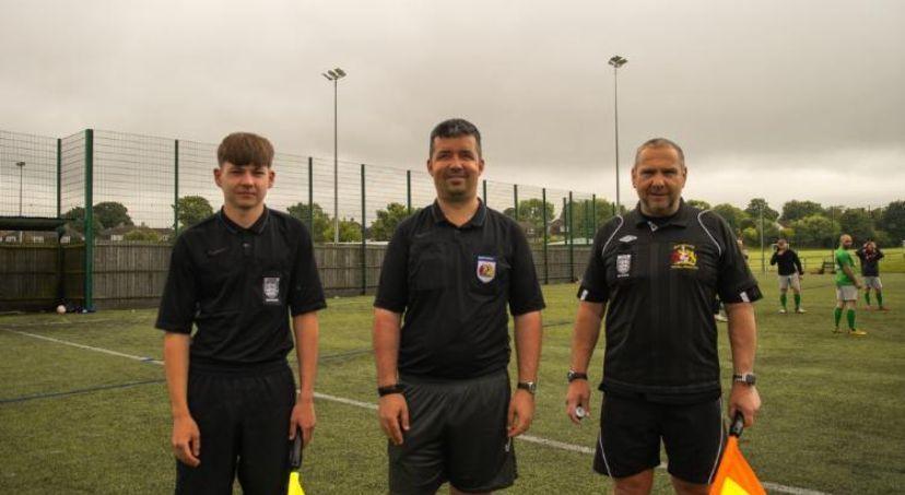 Michael Giblin with two other referees on a pitch