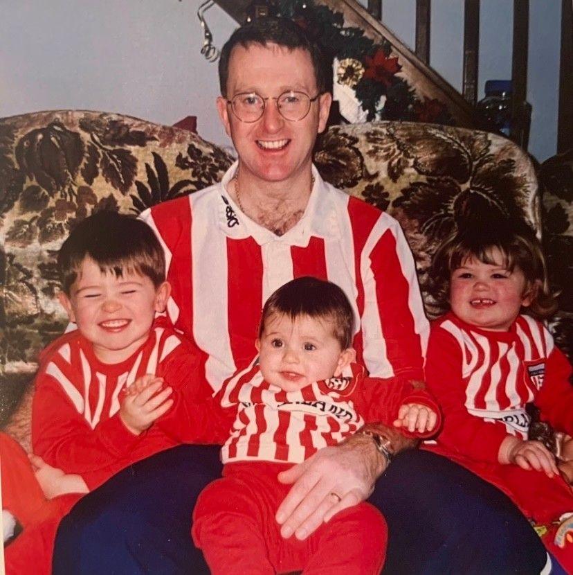 A man with three small children all dressed in Sunderland shirts
