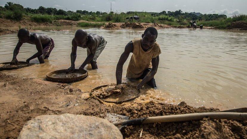 Three men sift through mud with circular sieves