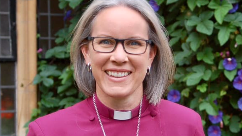 A portrait photograph of Bishop Ruth Bushyager, Bishop of Horsham, wearing her purple cassock.