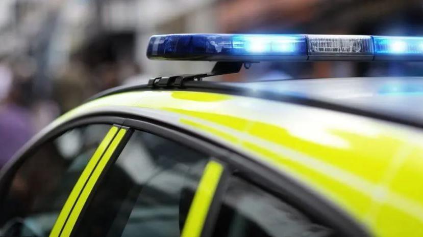 The top of a police car. The blue light is on. 