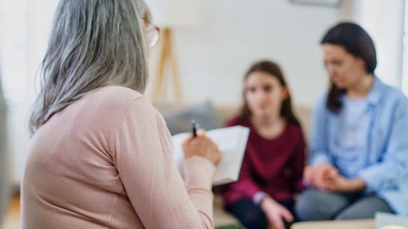 A clinician takes notes during an interview with a patient