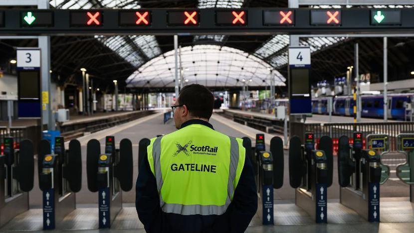 rail worker standing at station barriers