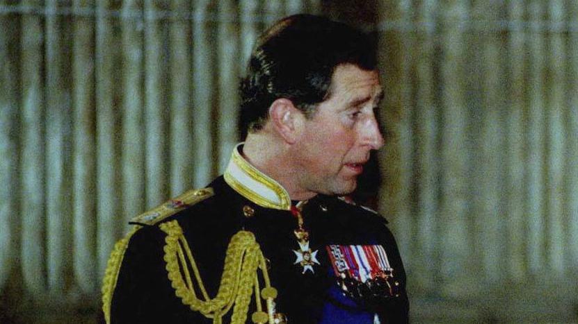 Pastaj Princi Çarls, një burrë në moshë të mesme i veshur me një uniformë ushtarake të zbukuruar me medalje.