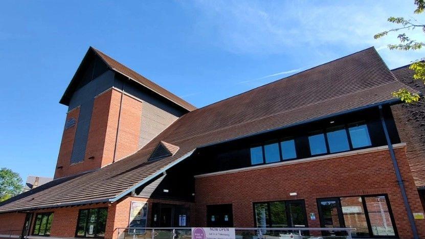 Exterior of the Castle Theatre in Wellingborough, a red-bricked double storey building with a glass-panelled ramp leading up to the entrance