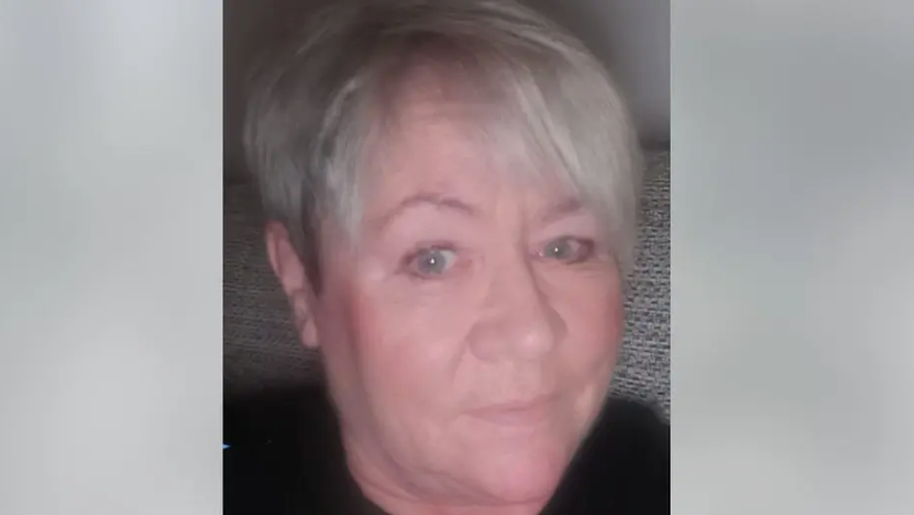 Kelly Faiers is looking ahead. She has silvery grey hair and is wearing a black top.
