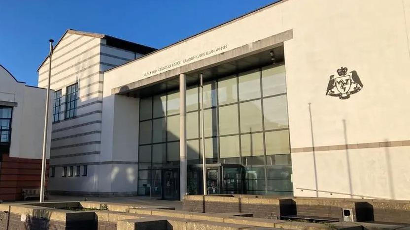 The Isle of Man Court of Justice building, which is a large white building with a glass front and the government crest on the wall.