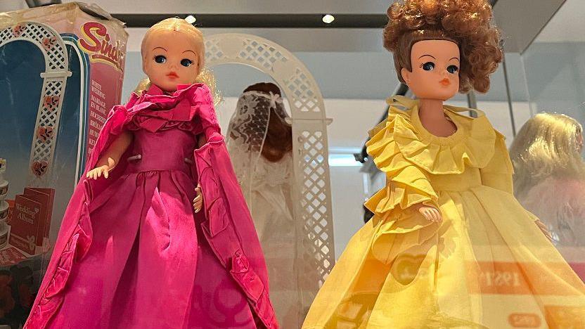 Two dolls in elaborate dresses, one bright pink, the other yellow