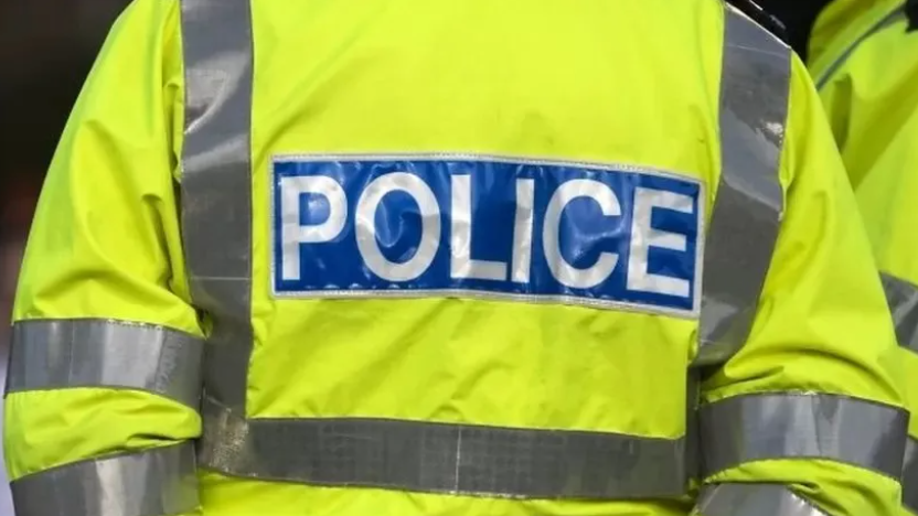 A cropped shot showing the back of a police officer's hi-vis jacket which reads 'Police'.