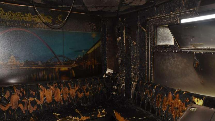 The fire-damaged barbers shop. The walls are black and the seats are burned.