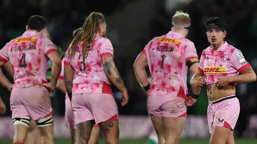 Harlequins player Marcus Smith looks dejected as his team-mates walk the other way with their backs to the camera