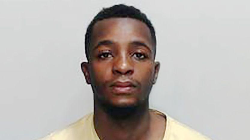 Police mugshot of a man with dark hair in a yellow t shirt