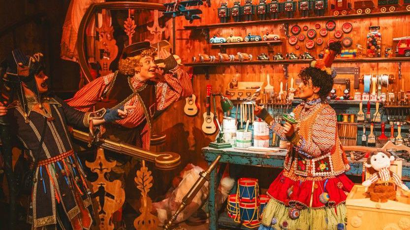 Workers in Santa's toy shop in their patchwork clothes of man hues with an assortment of multi-coloured musical instruments and other gifts