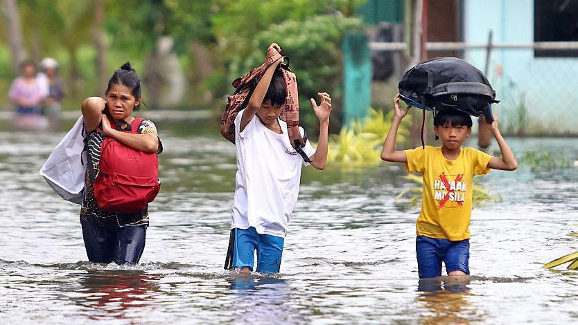 Residents evacuate from their flooded homes due to heavy rain brought by Typhoon Fung-wong in Remedios T Romualdez, on the southern island of Mindanao on November 8, 2025