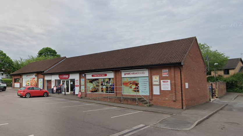 A Google Streetview showing the exterior of the One Stop in Walton. Six empty parking spaces can be seen outside the shop, with a red car parked outside the entrance.