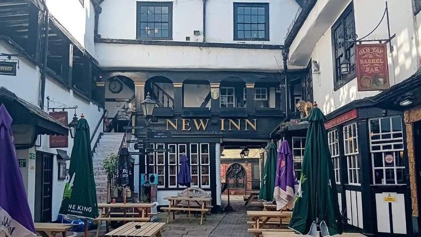 The New Inn courtyard in the daytime in white and black with pub benches laid out