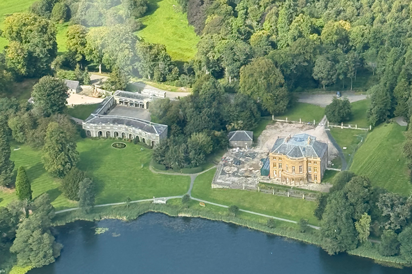 An aerial view of Haining House in the Scottish Borders and the surrounding estate and homes with a loch in the foreground