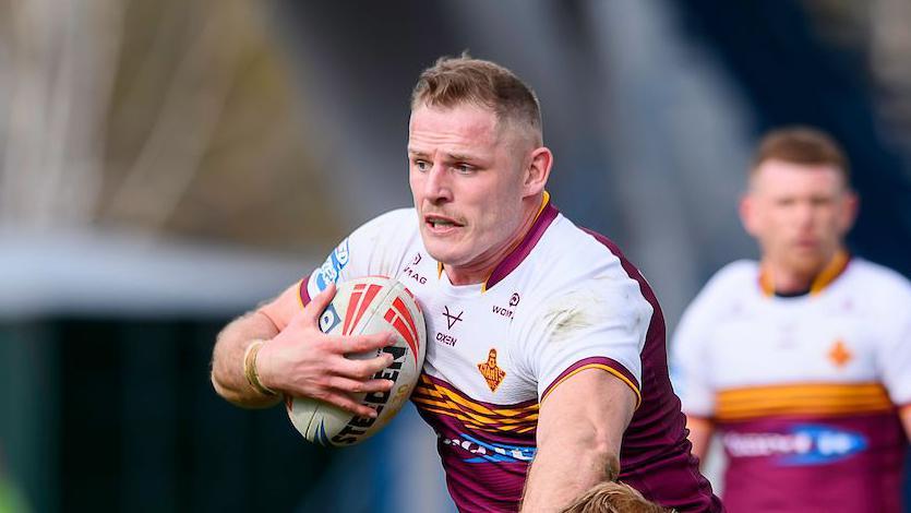 Tom Burgess carries the ball into contact under his right arm for Huddersfield Giants
