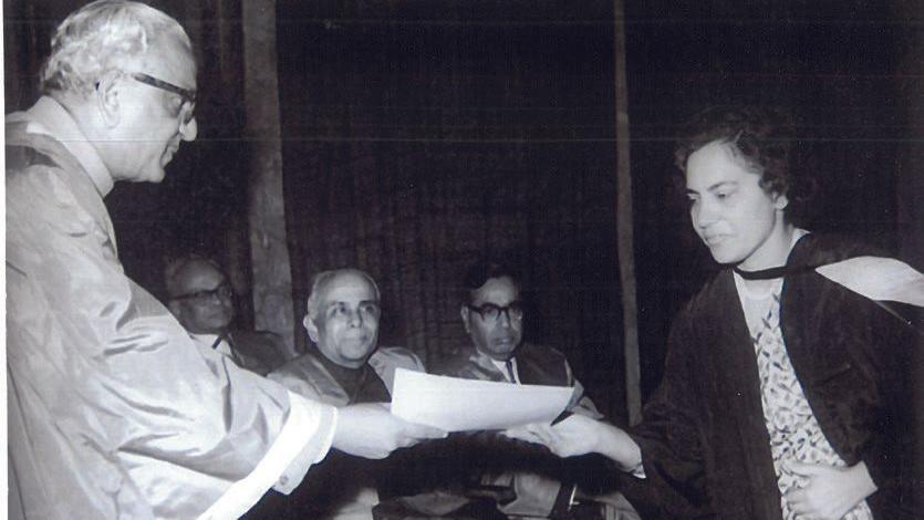 A black-and-white photo of Sneh Bhargava receiving a certificate from a man